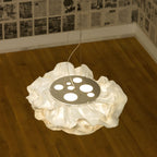 Seen from above, a Clérachic pendant rests on a timber floor, its frilled white shade around a round plate with circular cut-outs.