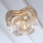 Looking up at the underside of this Clérachic pendant, its mesh shade spirals outward in layers against a white ceiling.
