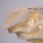 Close view of the frilled edge and perforated mesh of this Clérachic pendant, lit warm in a bright room.