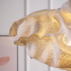 Close view of the folded layers and fine perforations on this Clérachic pendant shade, glowing gold against a soft backdrop.