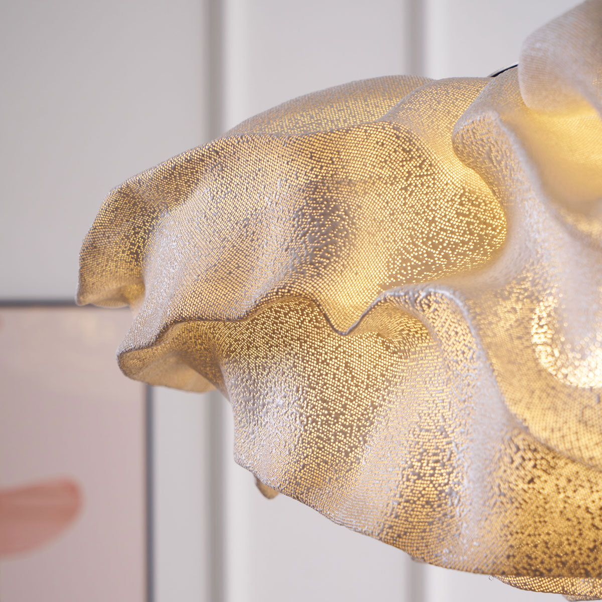 Close view of the folded layers and fine perforations on this Clérachic pendant shade, glowing gold against a soft backdrop.