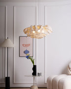 Beside a white panelled wall and a standing lamp, a Clérachic pendant hangs above a cream sofa and a small round table.