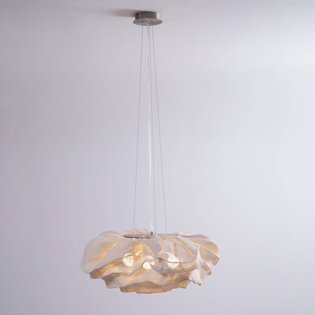 A Clérachic pendant with a round steel ceiling plate and a ruffled shade, lit against a pale grey backdrop.