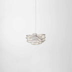 A small Clérachic pendant floating against a soft white backdrop on a single thin cord.