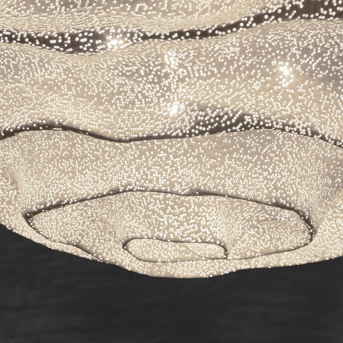 Close view of the lower layers of this Clérachic pendant shade, with the mesh dots lit and a dark backdrop beneath.