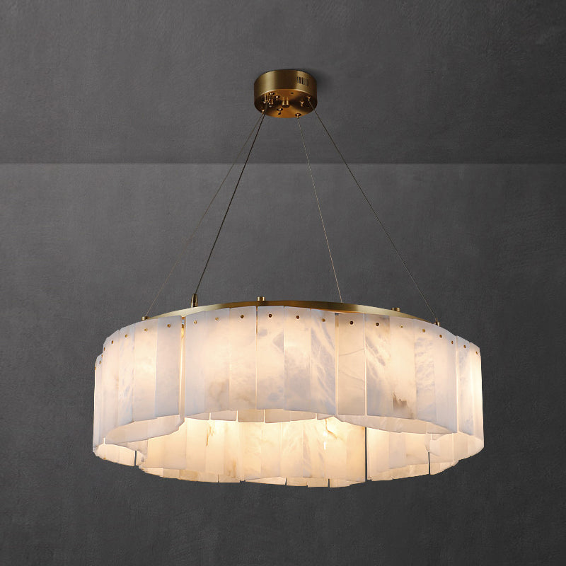 Clérachic Willamette Alabaster Drum Chandelier lit in a grey plaster room, its stone panels glowing honey-amber.