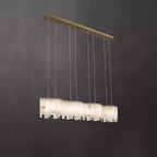 Clérachic Willamette Alabaster Drum Chandelier in its linear form, stone shades strung along a straight brass canopy.