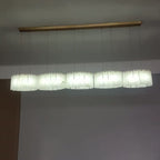 Clérachic Willamette Alabaster Drum Chandelier fitted to a white ceiling at home, its five linear shades lit bright.