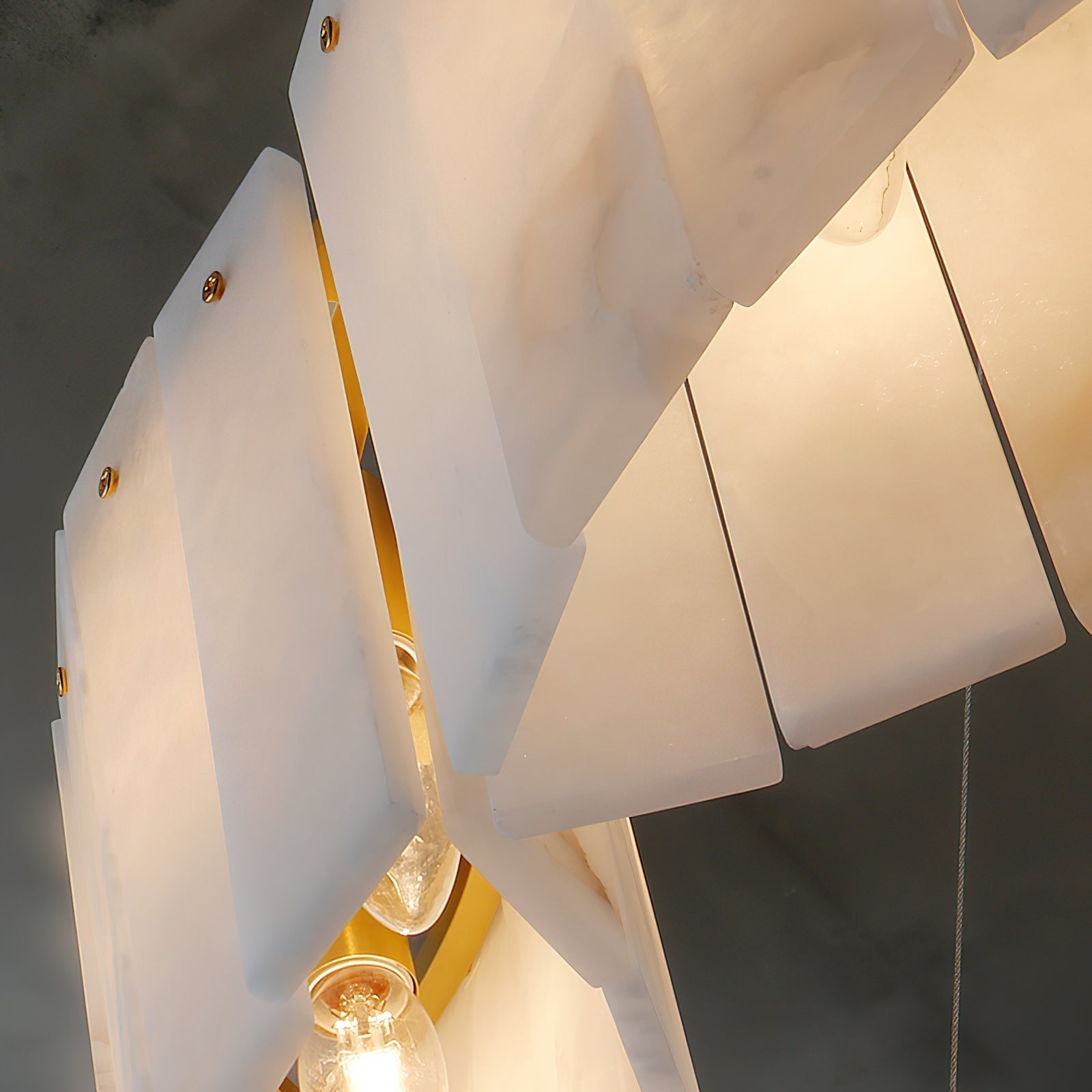 Clérachic Willamette Alabaster Drum Chandelier seen from below, lit bulbs backlighting the veined stone panels.