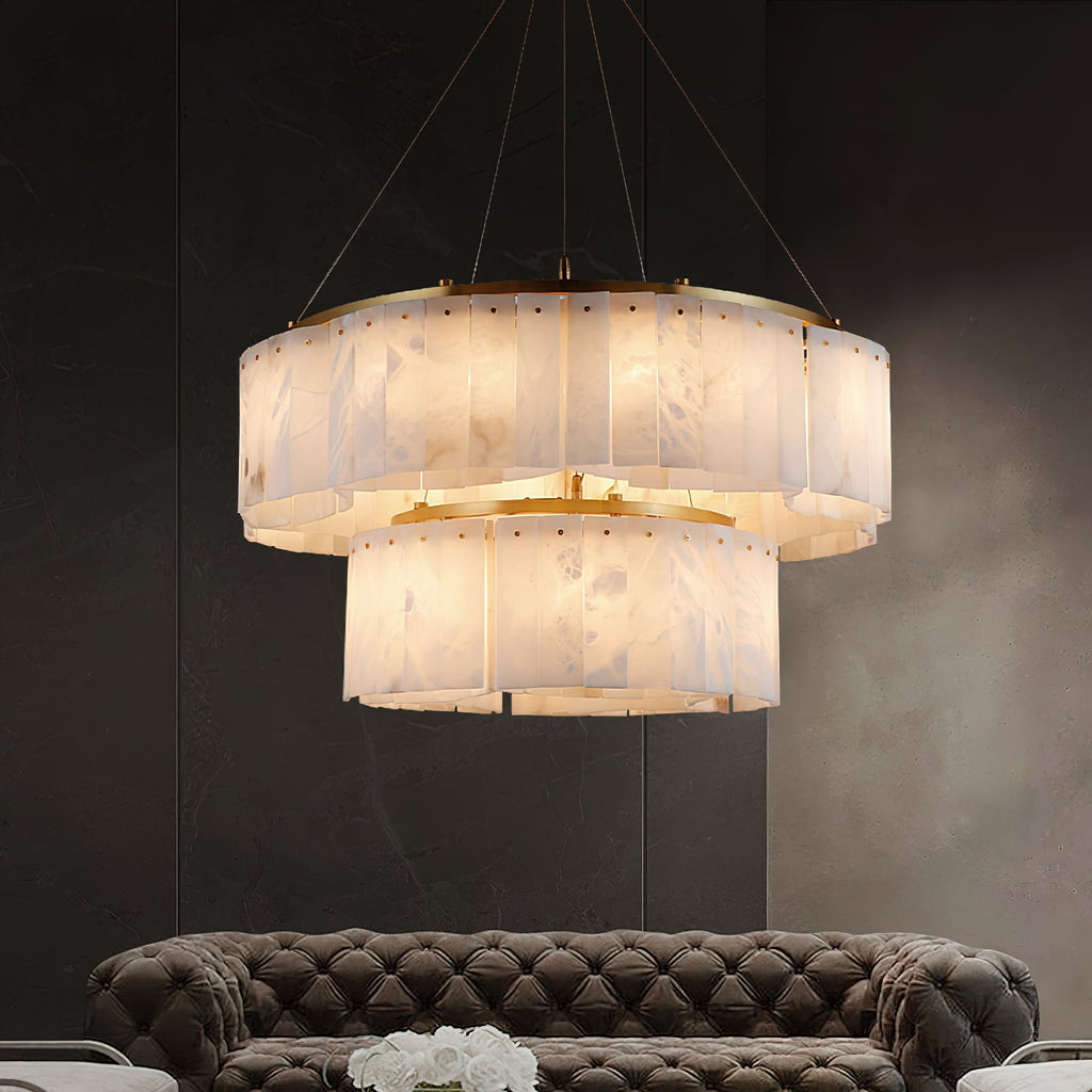 The Clérachic Willamette Alabaster Drum Chandelier lit above a tufted sofa in a dark marble lounge.