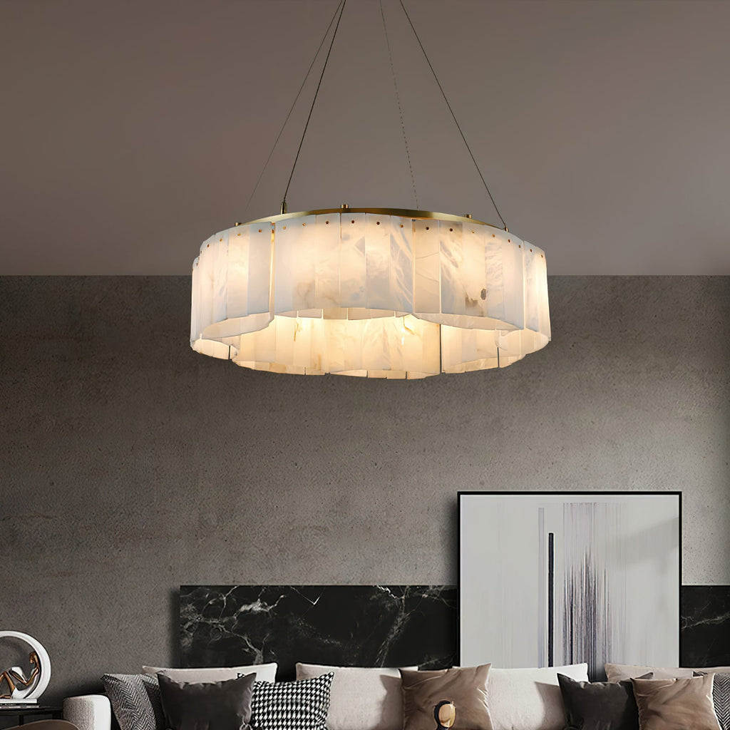 Clérachic Willamette Alabaster Drum Chandelier glowing over a concrete-walled living room with a low sofa and framed art.