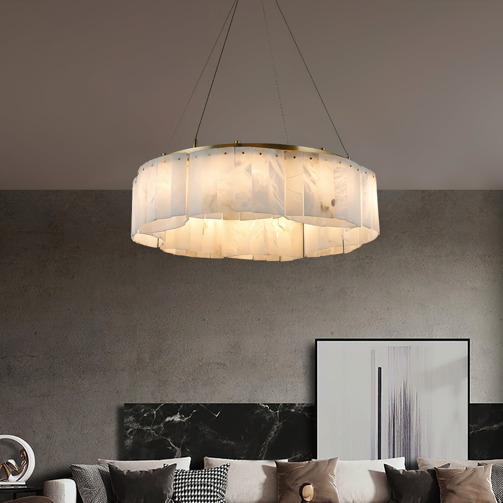 Clérachic Willamette Alabaster Drum Chandelier glowing over a concrete-walled living room with a low sofa and framed art.