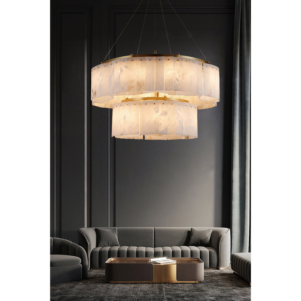The two-tier Clérachic Willamette Alabaster Drum Chandelier lighting a panelled salon above grey velvet sofas.