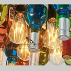Detail shot of the Clérachic wine bottle chandelier's included LED filament bulb, labelled and nestled among the coloured glass necks.