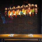 Clérachic Wine Bottle Glass Pendant Light hangs over a wooden dining table against a dark brick wall.