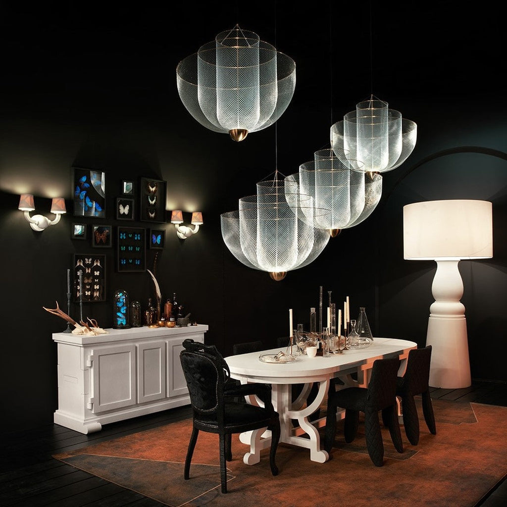 This Clérachic mesh chandelier hangs over a long white table in a dark room with a butterfly display, a sideboard and a tall floor lamp.