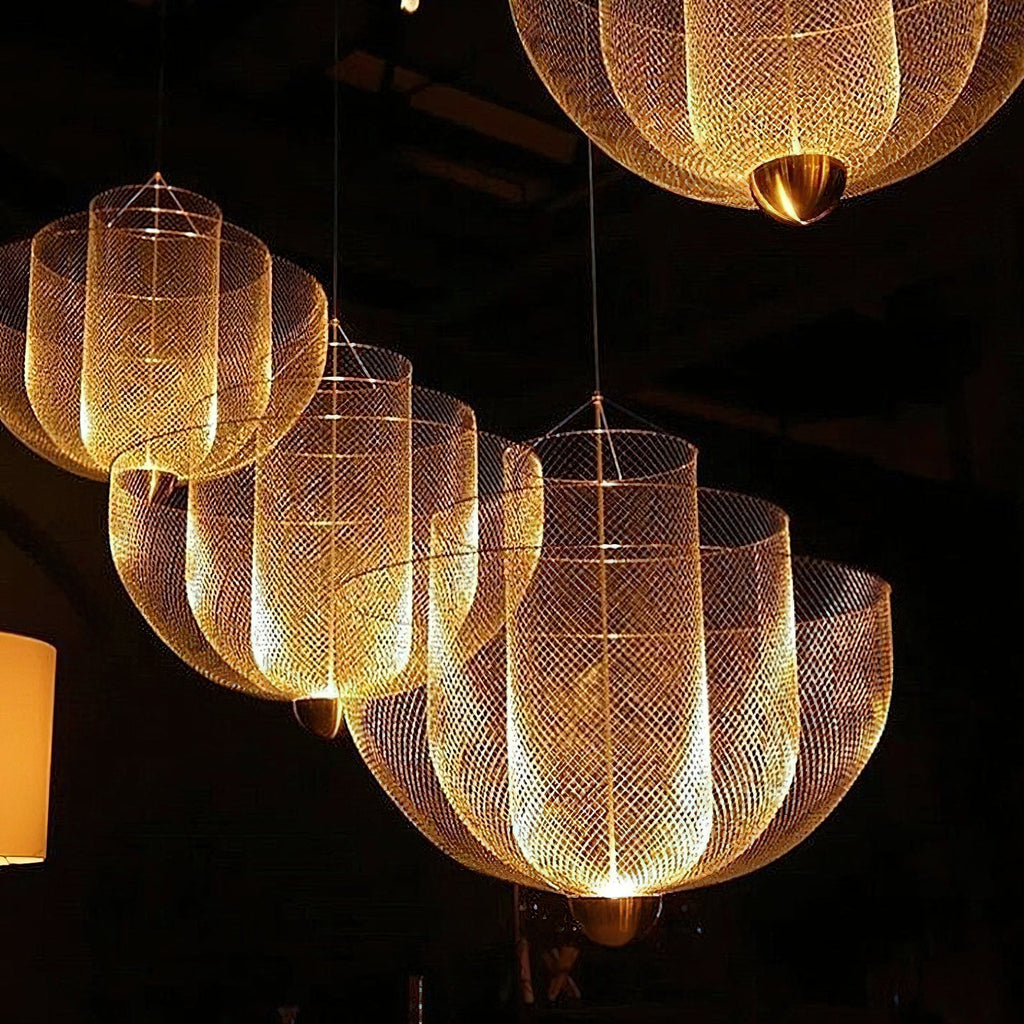 Several Clérachic gold-toned mesh chandeliers glow warm in a dark room, each with a brass orb at its base.