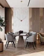A Clérachic mesh chandelier, with a brass orb at its base, in a dining room with a marble wall and tapered, upholstered chairs.