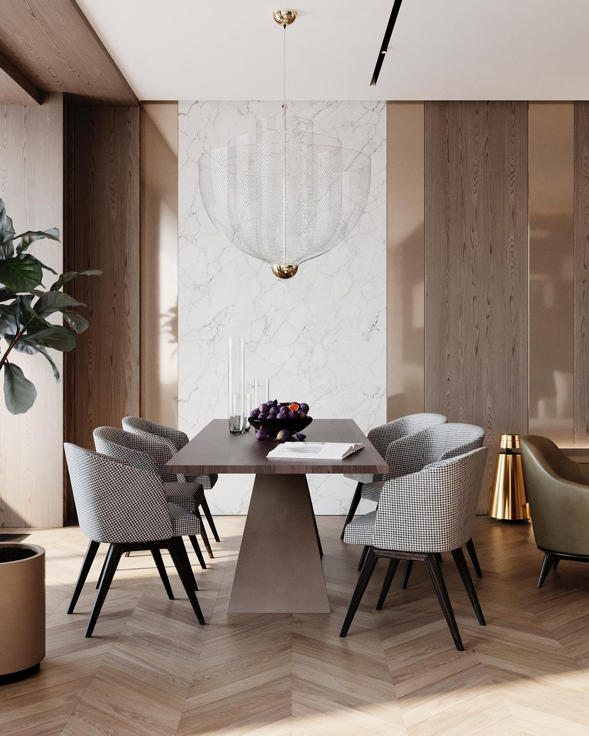 A Clérachic mesh chandelier, with a brass orb at its base, in a dining room with a marble wall and tapered, upholstered chairs.