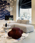 Clérachic wire-mesh chandelier in a bright showroom with a cream corner sofa, a round rug and a small side table.