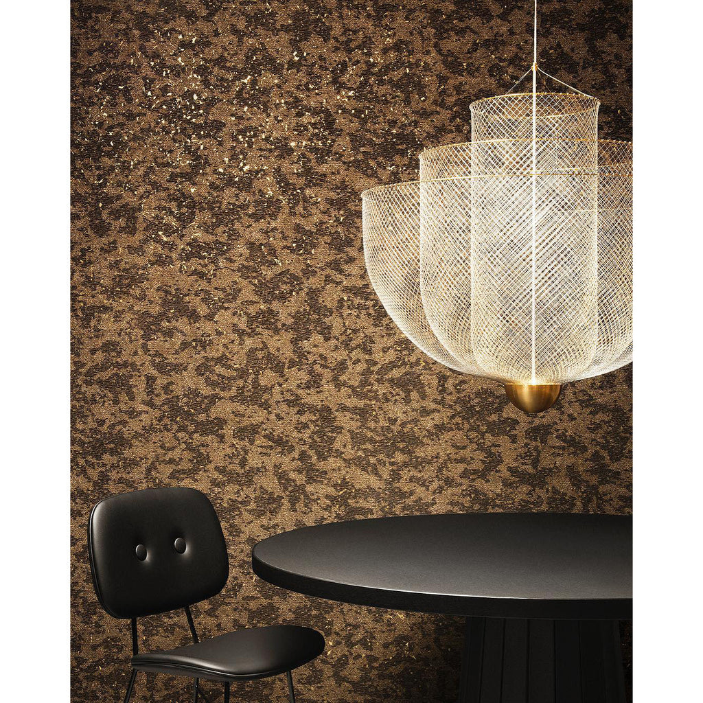 Clérachic wire-mesh chandelier on a gold-flecked dark wall, hung above a round black table, with a black chair beside it.