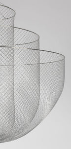 Side view of the wire-mesh bowls of this Clérachic chandelier, seen against a pale grey backdrop.