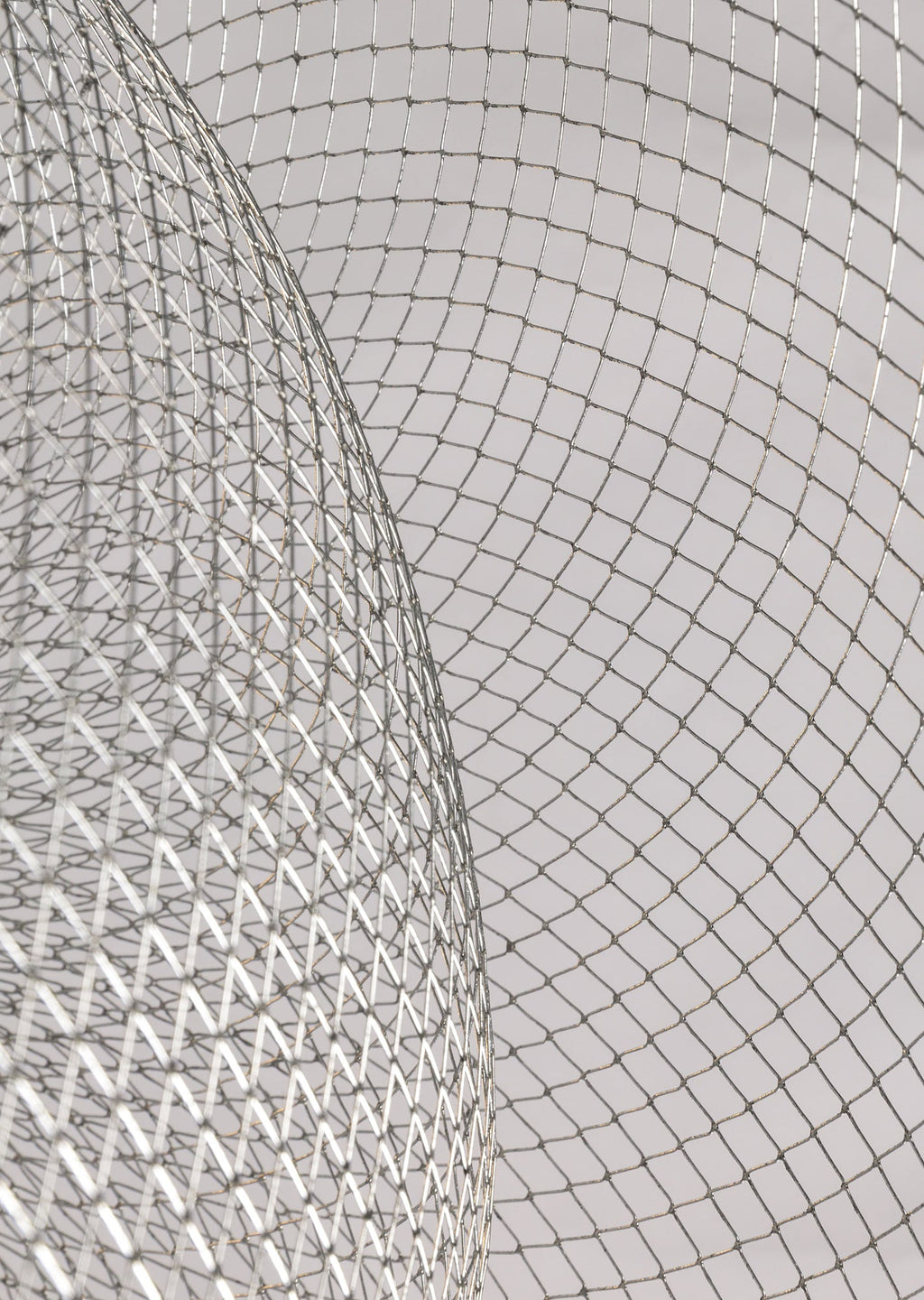 Close view of the criss-cross silver mesh on this Clérachic chandelier, with a curved bowl edge in the foreground.