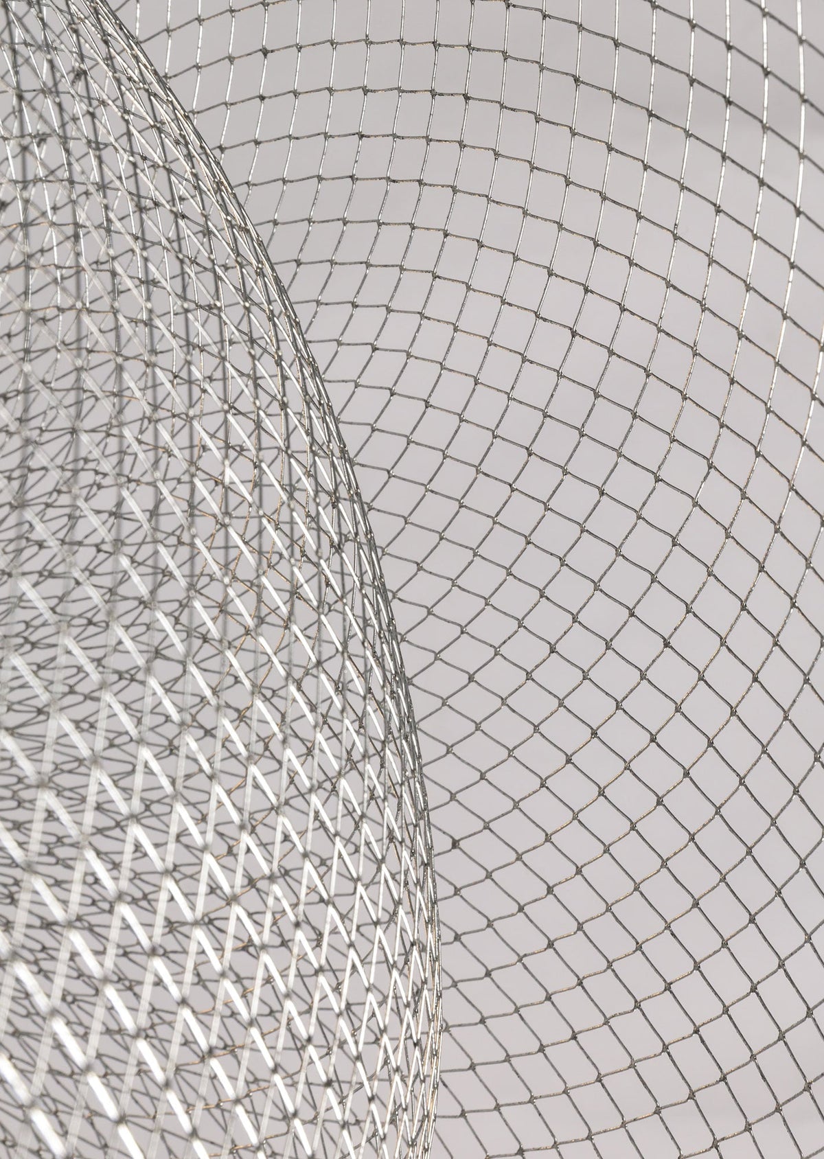 Close view of the criss-cross silver mesh on this Clérachic chandelier, with a curved bowl edge in the foreground.