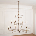 Clérachic's Wisp Grande chandelier hangs lit above a wood floor, its bulbs glowing warm in a paneled room.