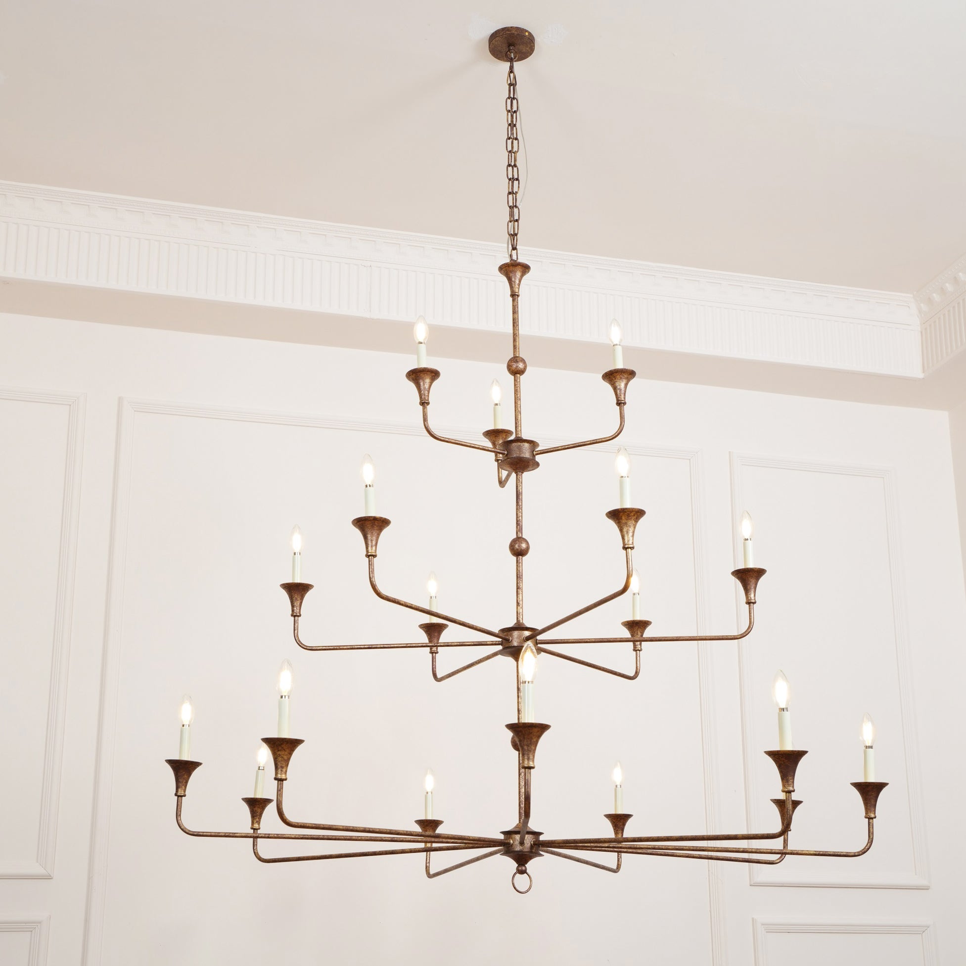 The Clérachic Wisp Grande chandelier glows from a different angle, bronze tiers against a wainscoted wall.
