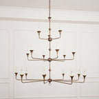 Clérachic's Wisp Grande chandelier centered head-on, all three lit tiers spreading wide above a paneled room.