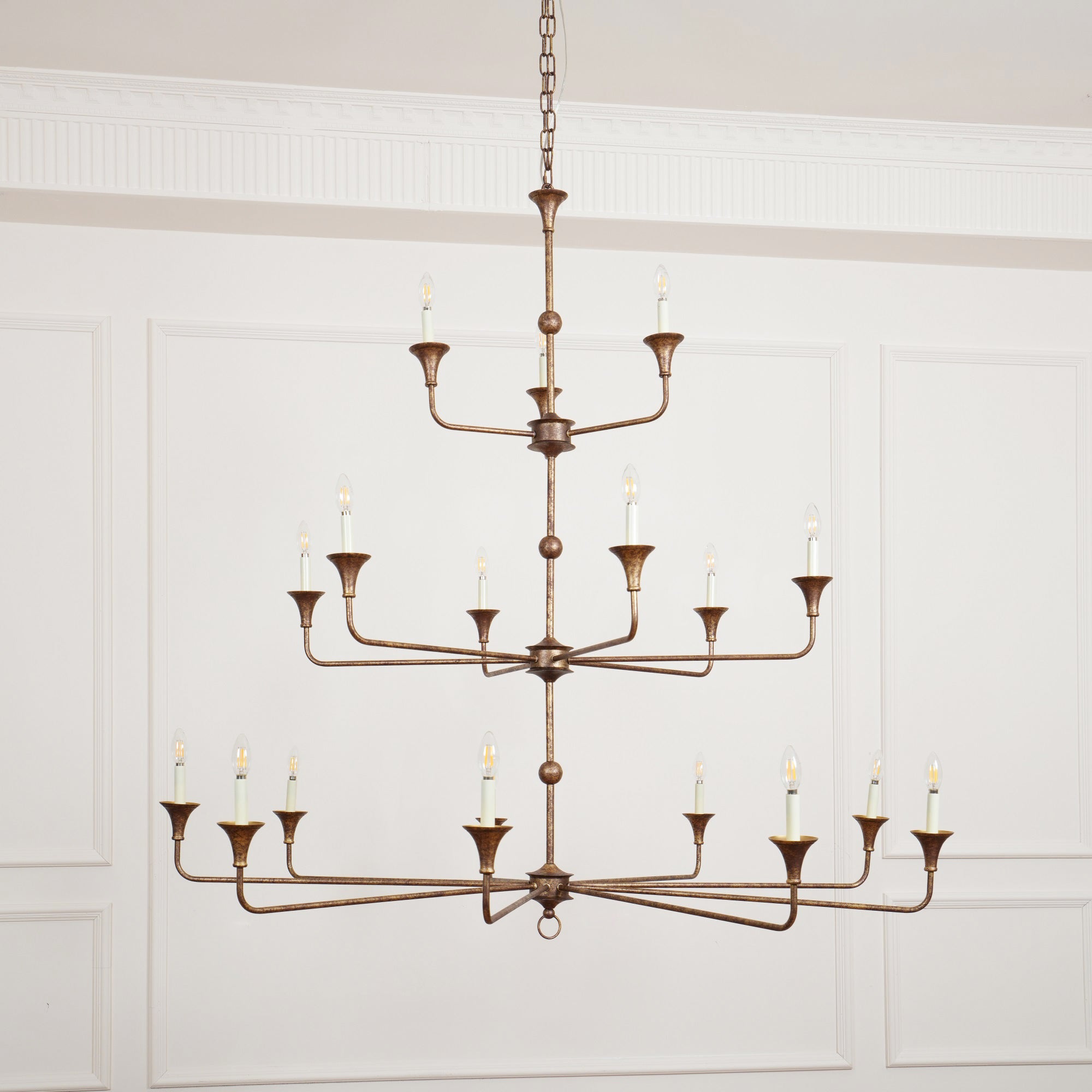 Clérachic's Wisp Grande chandelier centered head-on, all three lit tiers spreading wide above a paneled room.