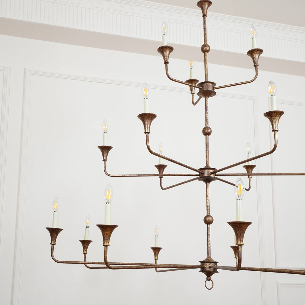 Clérachic's Wisp Grande chandelier fills a wide room shot, its 18 lit arms spread across three bronze tiers.