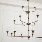 Clérachic's Wisp Grande chandelier fills a wide room shot, its 18 lit arms spread across three bronze tiers.