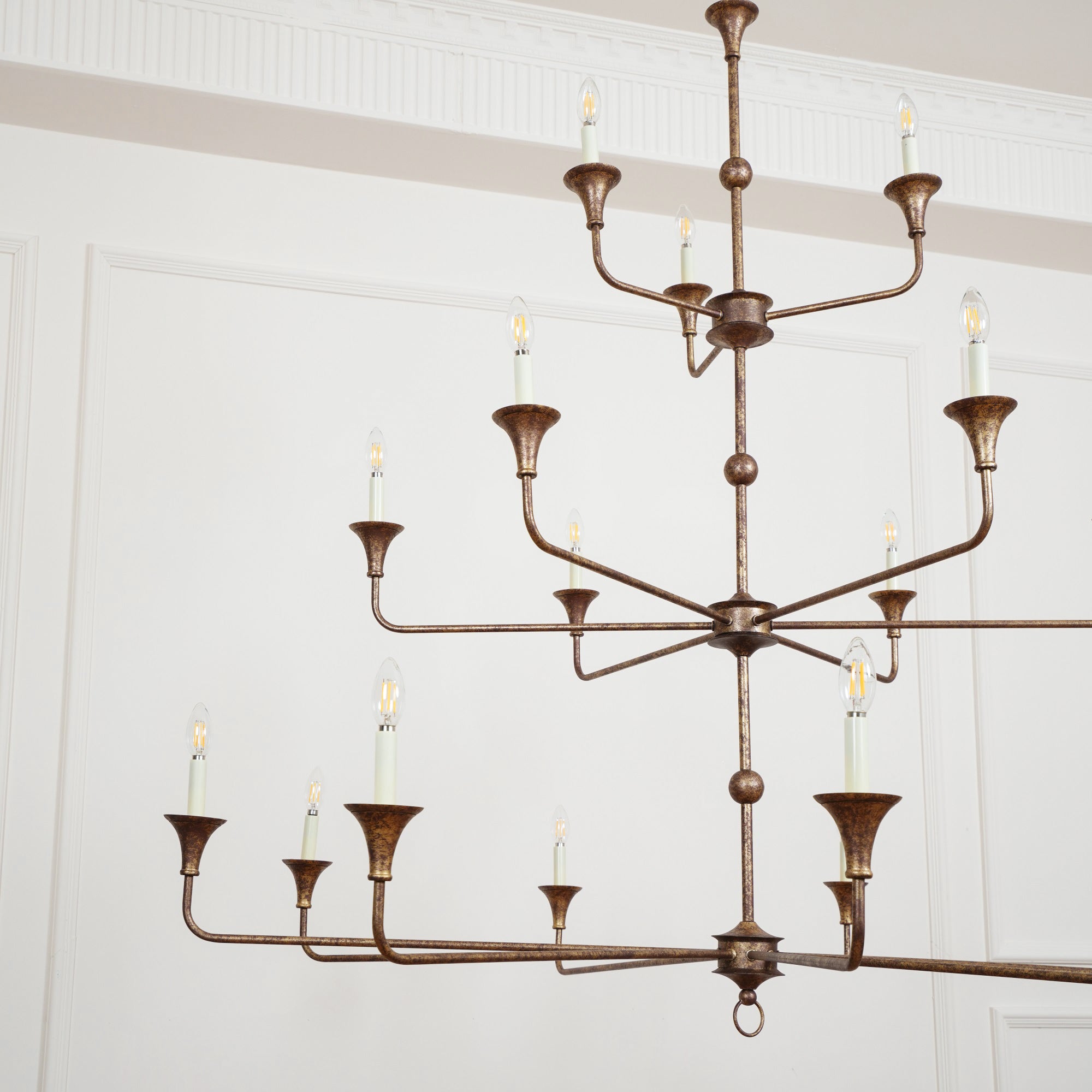 Clérachic's Wisp Grande chandelier fills a wide room shot, its 18 lit arms spread across three bronze tiers.