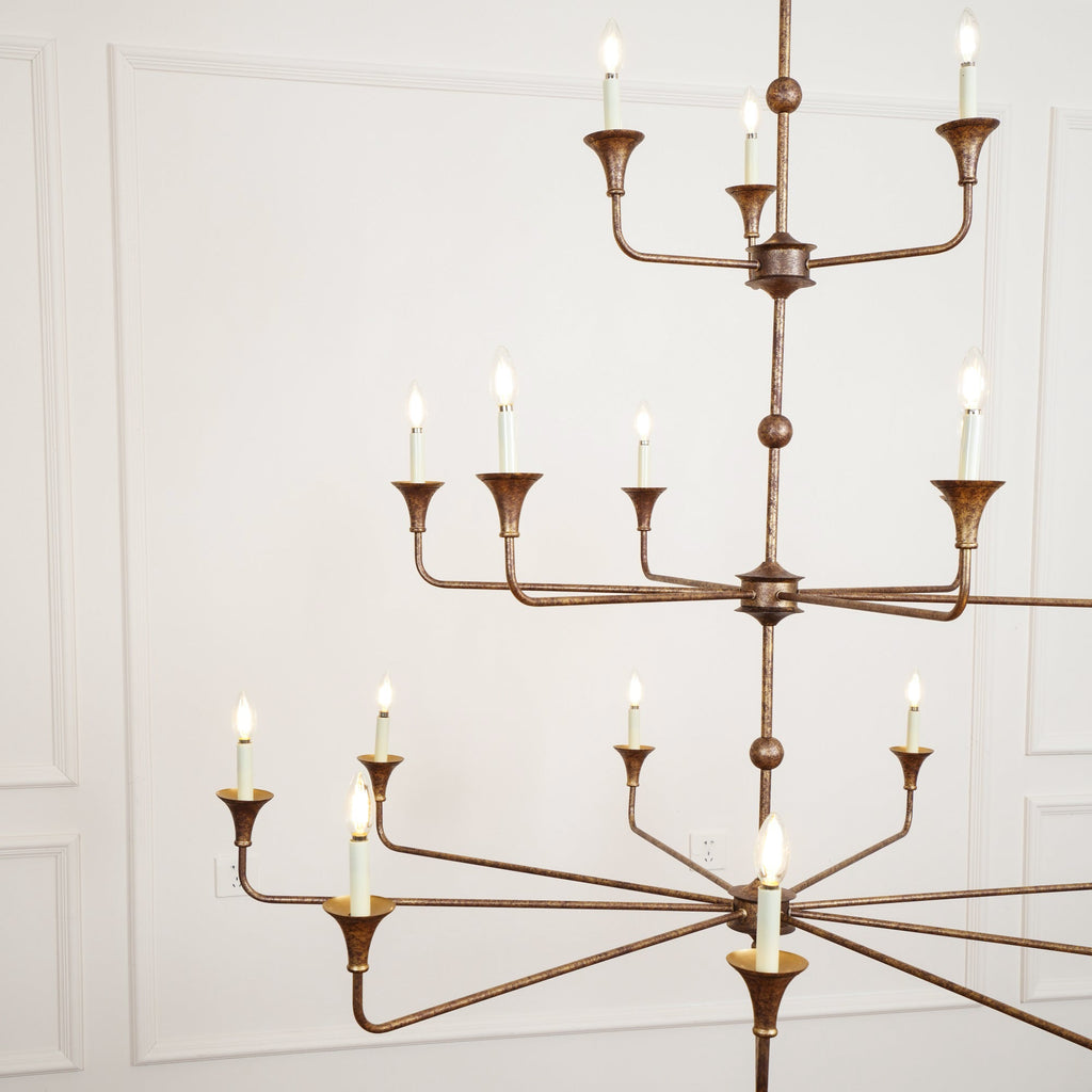 The Clérachic Wisp Grande chandelier photographed from a lower angle, bronze tiers glowing warm indoors.