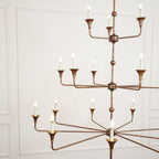 The Clérachic Wisp Grande chandelier photographed from a lower angle, bronze tiers glowing warm indoors.