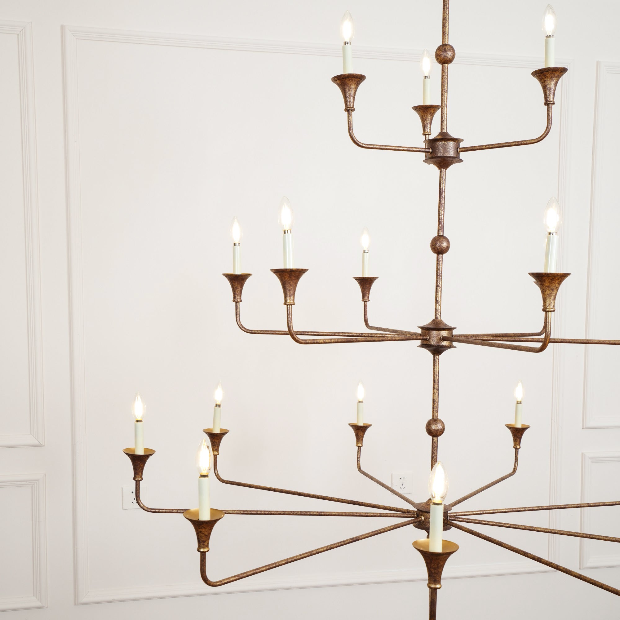 The Clérachic Wisp Grande chandelier photographed from a lower angle, bronze tiers glowing warm indoors.