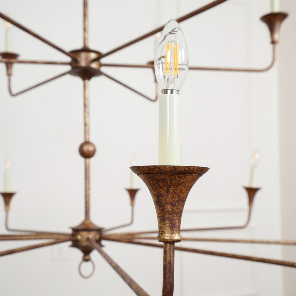 Clérachic's Wisp Grande chandelier in close-up, a lit Edison-style filament bulb glowing in one E14 socket.