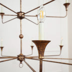 Clérachic's Wisp Grande chandelier in close-up, a lit Edison-style filament bulb glowing in one E14 socket.