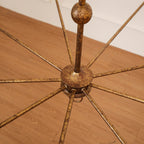 The Clérachic Wisp Grande chandelier's bronze center hub photographed close on a wood floor, arms fanning out.