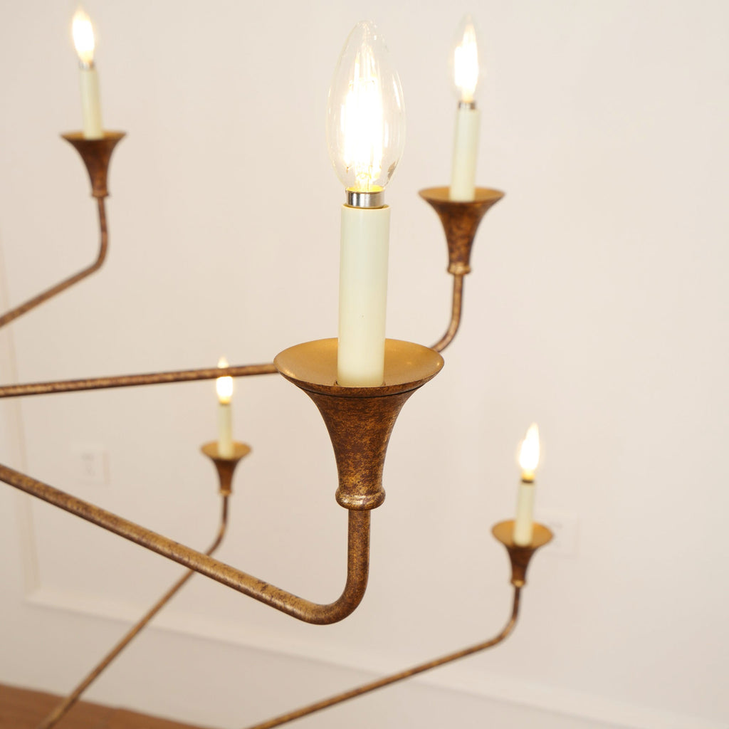 Clérachic's Wisp Grande chandelier up close, two Edison-style filament bulbs lit in their bronze sockets.