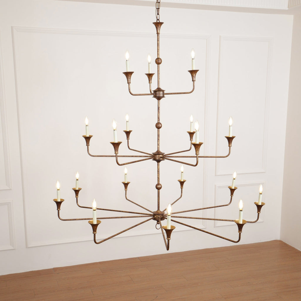 The Clérachic Wisp Grande chandelier's 18 lit arms glow symmetrically against a wainscoted wall.