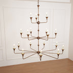 The Clérachic Wisp Grande chandelier's 18 lit arms glow symmetrically against a wainscoted wall.
