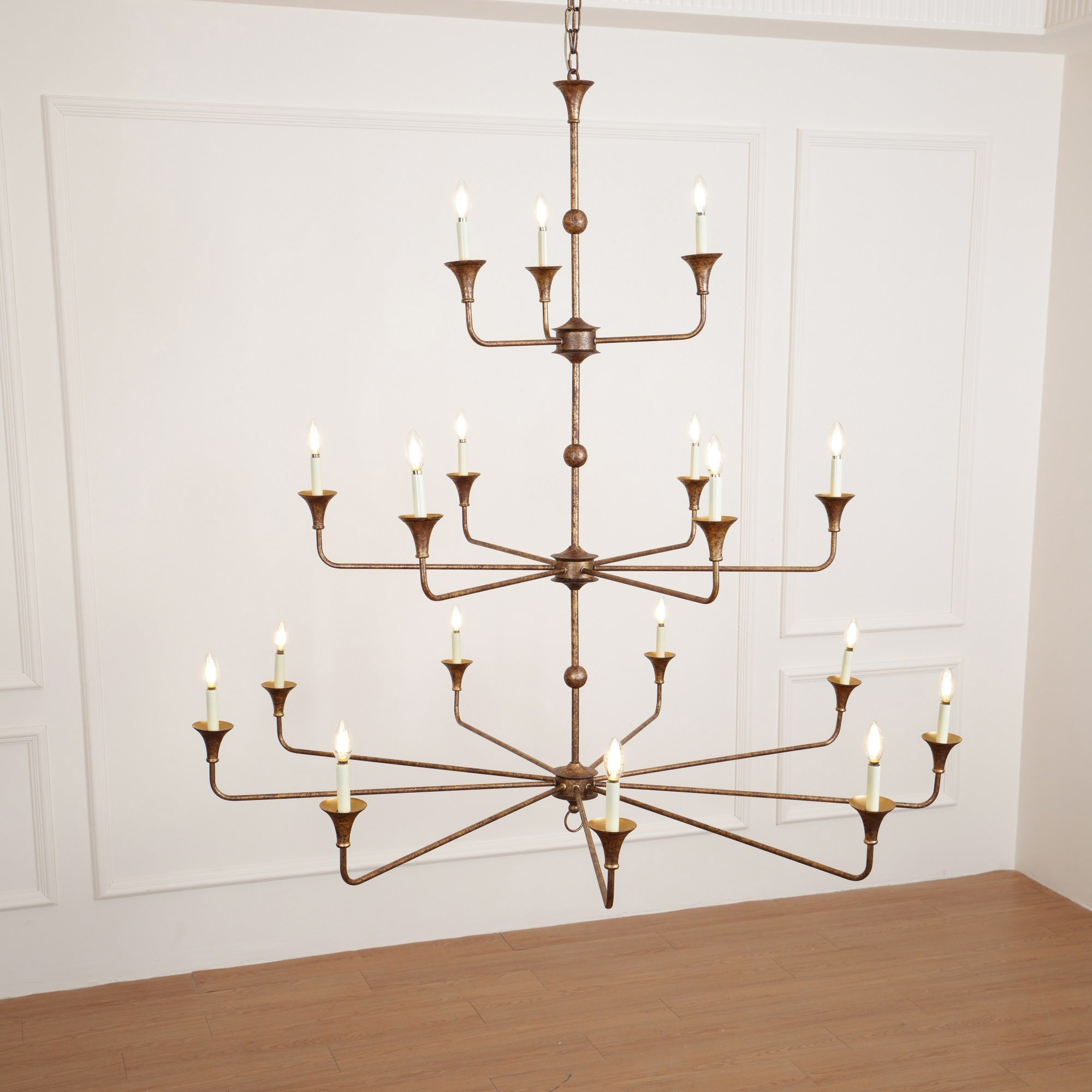 The Clérachic Wisp Grande chandelier's 18 lit arms glow symmetrically against a wainscoted wall.