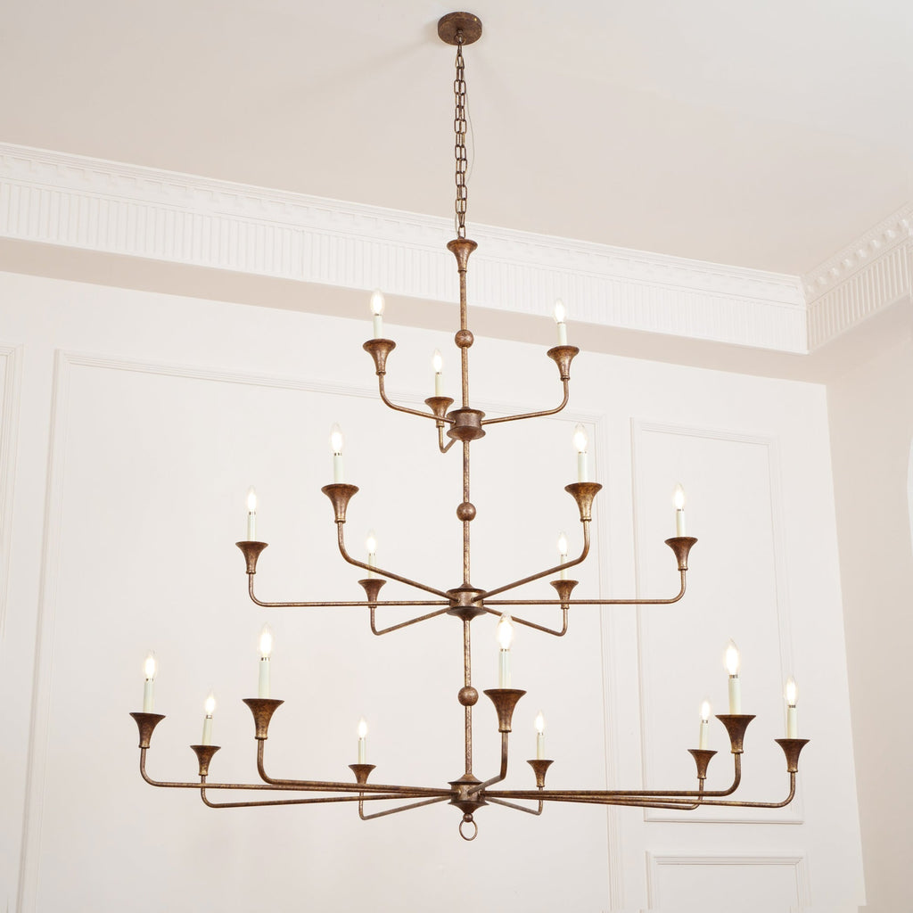 The Clérachic Wisp Grande chandelier hangs high on its chain, bronze arms glowing across three tiers.
