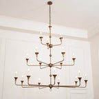 The Clérachic Wisp Grande chandelier hangs high on its chain, bronze arms glowing across three tiers.
