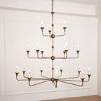 Clérachic's Wisp Grande chandelier closes the gallery with its 18 lit arms glowing warm in a paneled room.