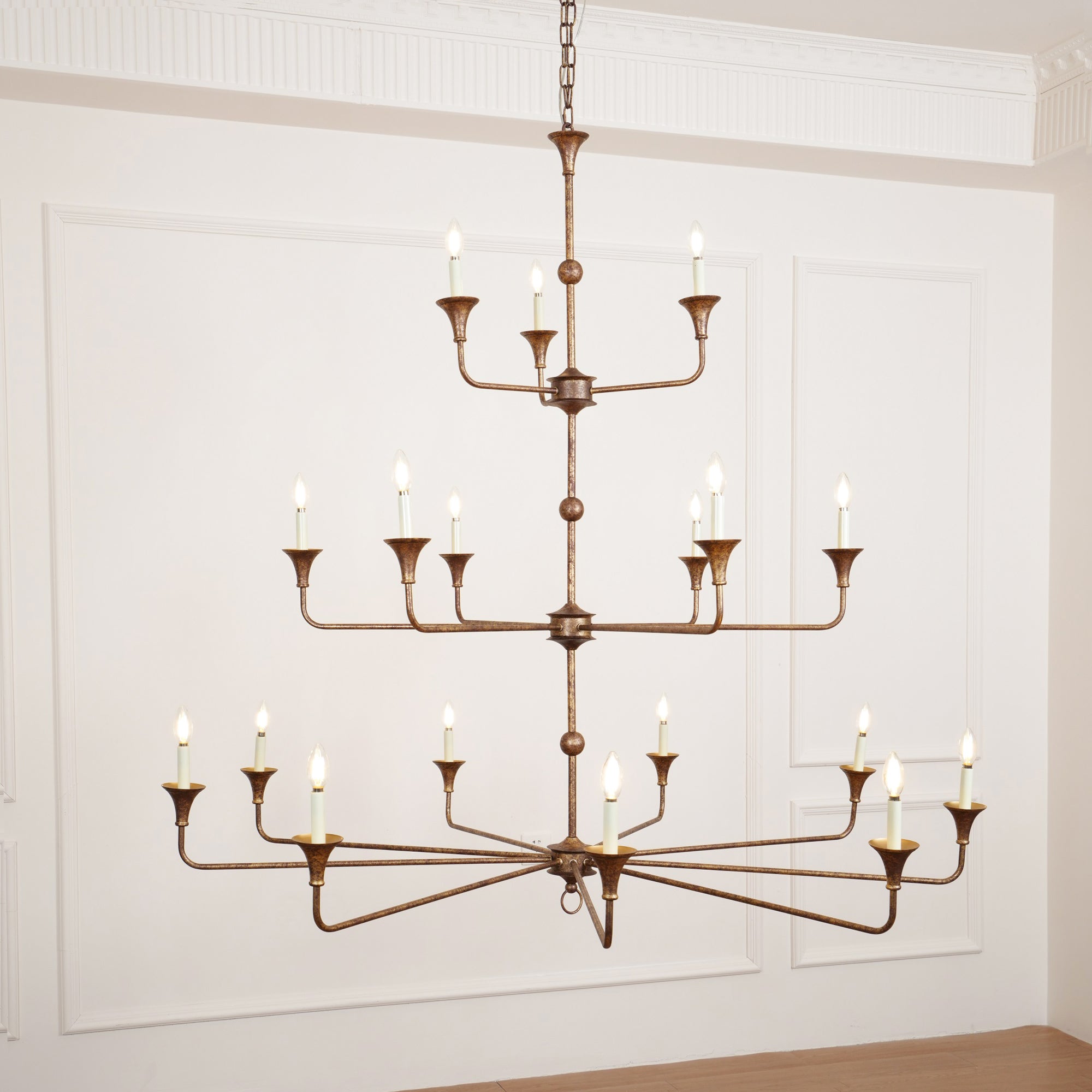 Clérachic's Wisp Grande chandelier closes the gallery with its 18 lit arms glowing warm in a paneled room.