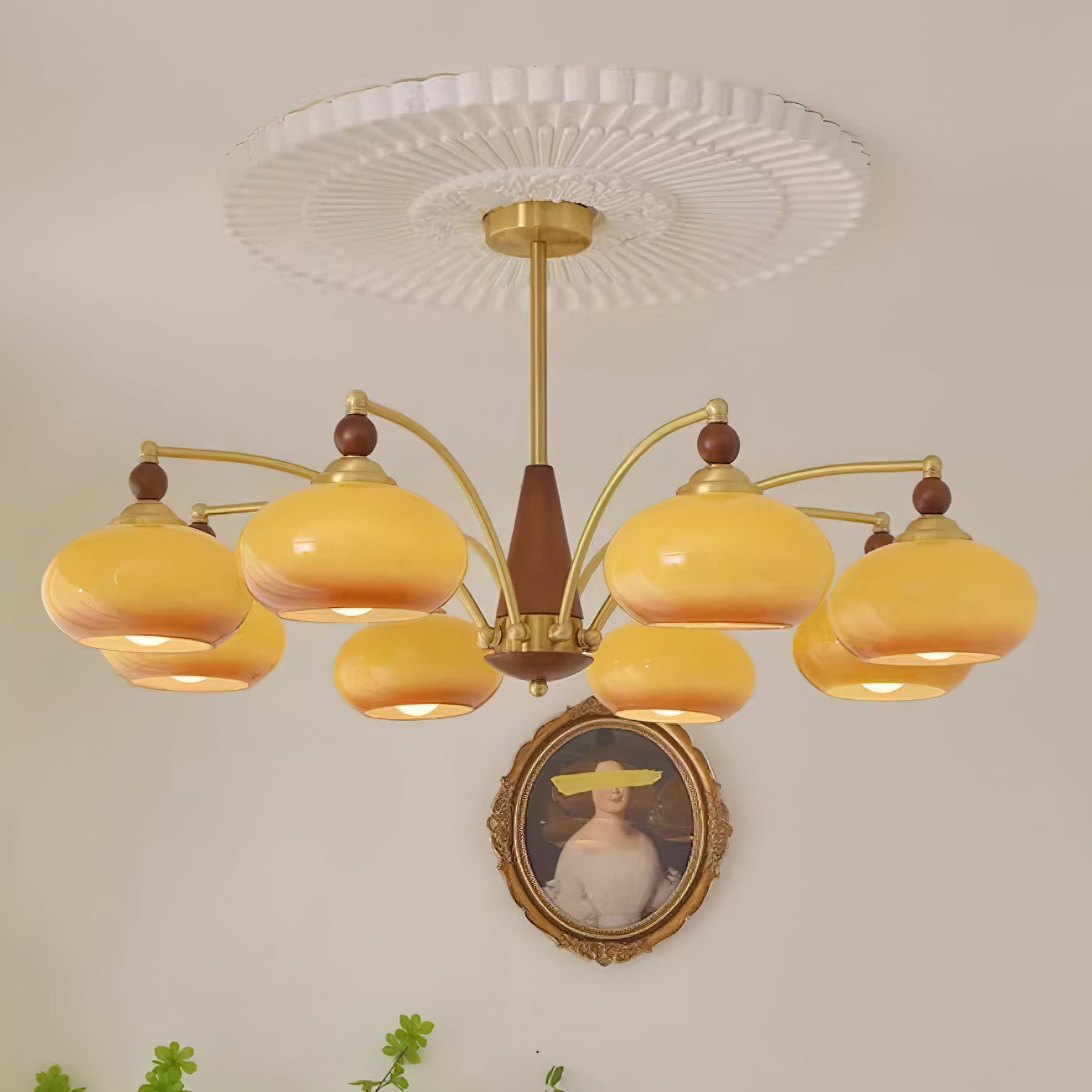 Clérachic Wood and Brass Chandelier in caramel, eight shades lit above a gilt-framed portrait on a pale wall.